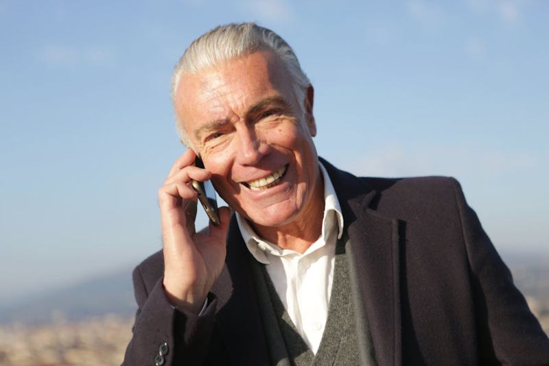 Smiling older man talking on a smartphone outdoors, illustrating how constant contact can mask emotional distance, why modern communication makes you feel lonely