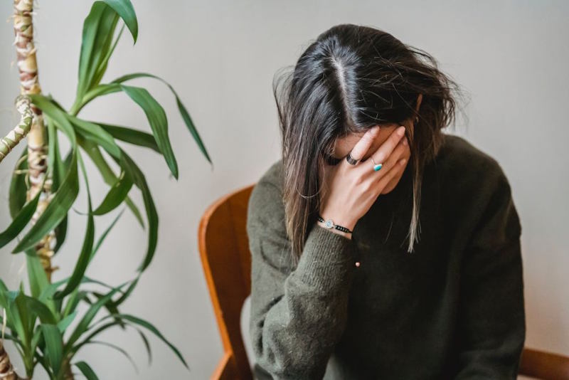 Person sitting alone indoors with head in hands, reflecting emotional disconnection and feelings of loneliness despite constant communication